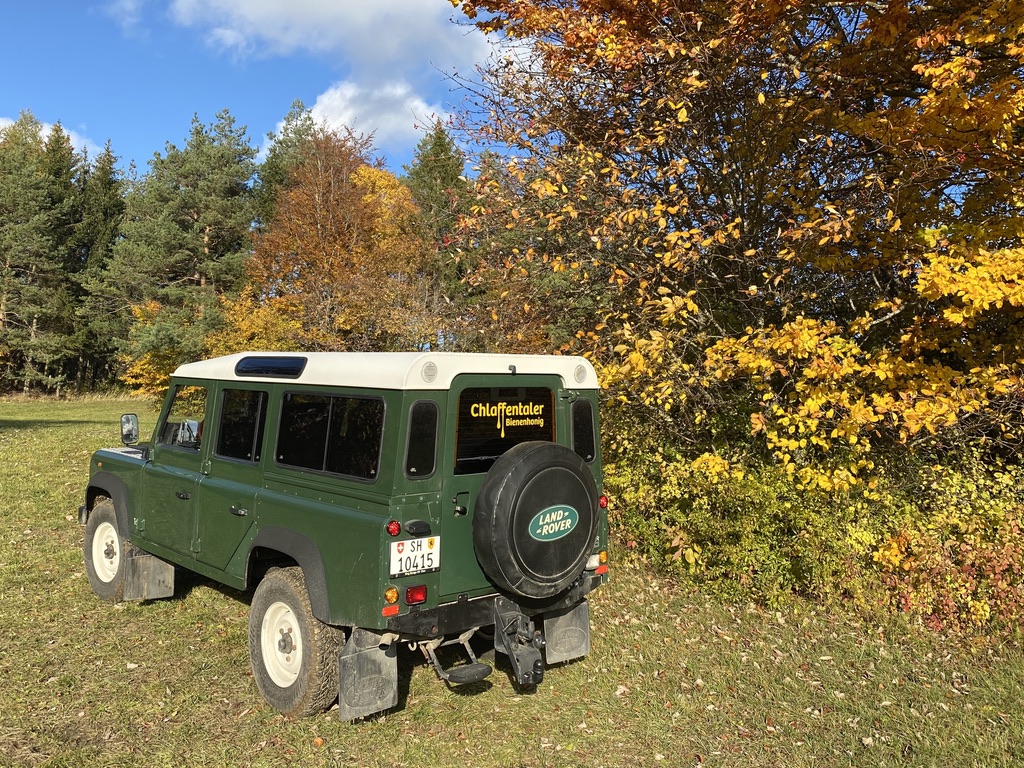 Land Rover Defender mit Chlaffentaler Bienenhonig Beschriftung im Herbstwald